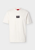 Weißes T-Shirt mit kurzen Ärmeln und Rundhalsausschnitt, versehen mit einem kleinen schwarzen rechteckigen Aufnäher und weißem "HUGO"-Schriftzug auf der Brust.