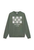 Grüne Sweatshirt mit langen Ärmeln und Rundhals. Die Vorderseite zeigt weiße Blockbuchstaben und Text, mit gerippten Bündchen und Saum. Glatte Textur.