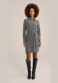 Schwarz-weiß gemustertes Kleid mit Kragen, langen Ärmeln, einem elastischen Bund und einem gebundenen Gürtel, kombiniert mit schwarzen kniehohen Stiefeln.
