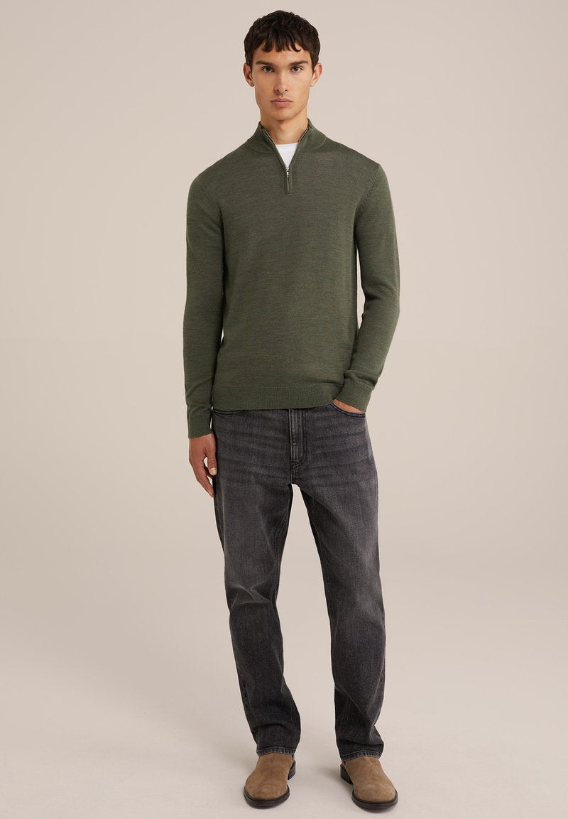 Dunkelgrüner Reißverschluss-Pullover mit körperbetontem Design, getragen über einem weißen Hemd. Kombiniert mit grauen Jeans und hellbraunen Schuhen. Glatte Textur, minimalistischer Stil.