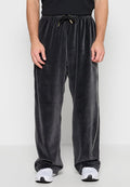 Schwarze lockere Velours-Hose mit elastischem Bund und Kordelzug, getragen mit weißen Sneakers und einem schwarzen Hemd.