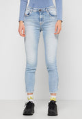 Hellblaue Jeans im Slim-Fit-Stil mit fransigem Saum und subtilen Verwaschungen. Getragen mit schwarzen Sportschuhen und gemusterten weißen Socken.