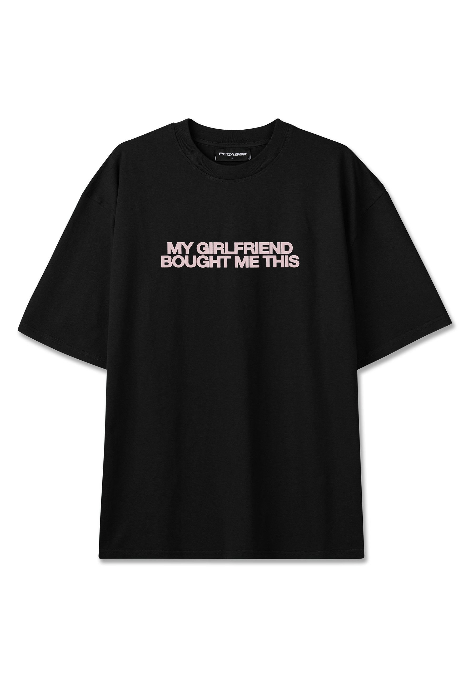 Schwarzes kurzärmeliges T-Shirt mit pinkem Text "MY GIRLFRIEND BOUGHT ME THIS" mittig auf der Brust, Rundhalsausschnitt, lockerer Schnitt.