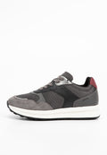 Graue Sneaker aus einer Kombination von Wildleder und Mesh-Materialien, mit schwarzen Lederelementen und einer kastanienbraunen Fersenpartie auf einer weißen Sohle.