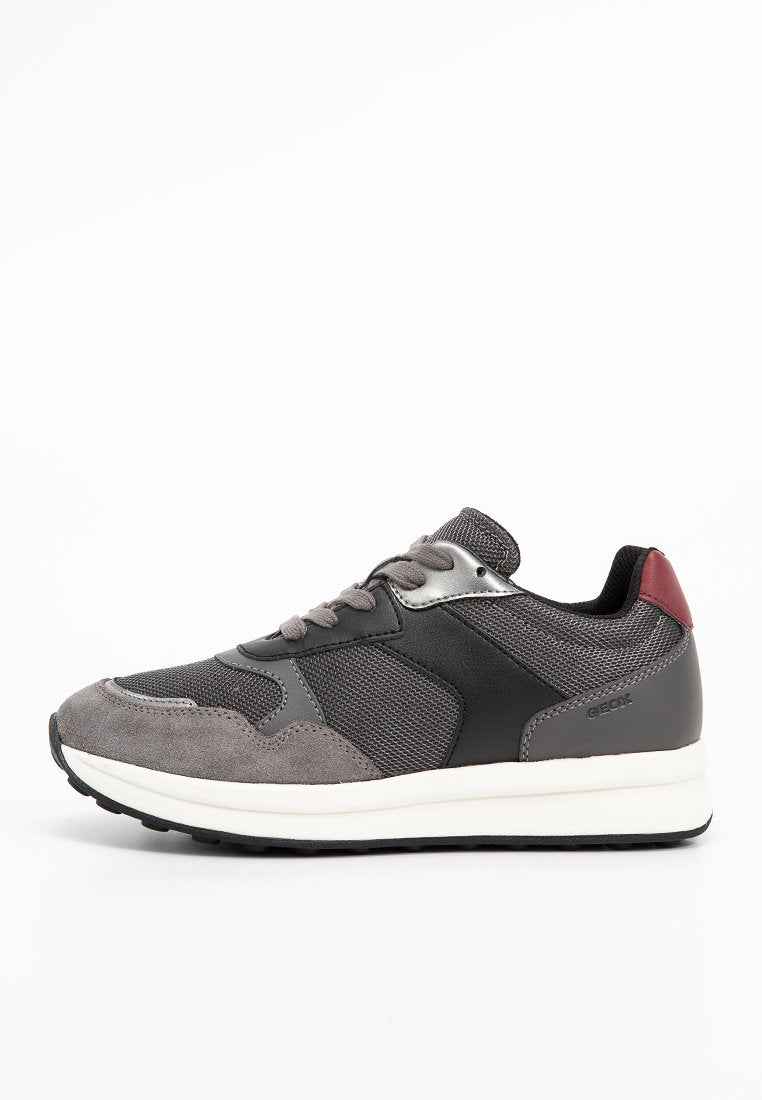 Graue Sneaker aus einer Kombination von Wildleder und Mesh-Materialien, mit schwarzen Lederelementen und einer kastanienbraunen Fersenpartie auf einer weißen Sohle.