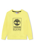 Gelbes Sweatshirt aus weichem Material mit einem schwarzen Grafikdesign eines Baumes und dem Text: "TIMBERLAND BUILT FOR THE BOLD", mit gerippten Bündchen.