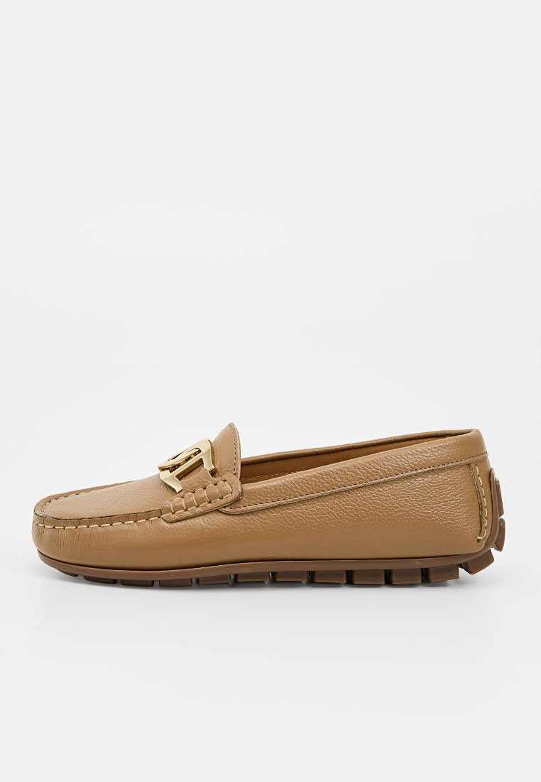 Hellbrauner Leder-Slipper mit goldener Schnalle und segmentierter Gummisohle, seitlich auf weißem Hintergrund gezeigt.