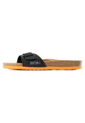 Schwarze Slide-Sandale mit strukturiertem Obermaterial, verstellbarem Riemen, Korkfußbett und orangefarbener Gummisohle. Mit "BAYTON"-Markenaufdruck an der Seite.