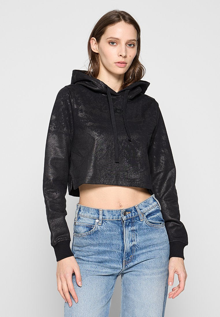 Schwarze, kurz geschnittene Kapuzenjacke mit strukturierter Oberfläche, mit Kapuze und lockerer Passform. Kombiniert mit hoch geschnittenen, hellblauen Jeans.