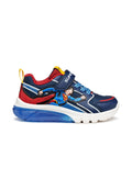 Blaue Sneakers mit roten Akzenten, featuring einem Superman-Grafik, Klettverschluss, flacher weißer Sohle und einer transparenten blauen Sohleneinheit.