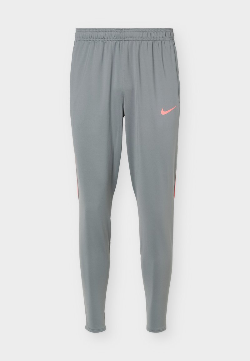 Graue Sporthose mit elastischem Bund und schmaler Passform, mit einem kleinen pinken Nike-Swoosh-Logo am rechten Oberschenkel.