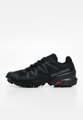 Schwarzer Salomon Trailrunning-Schuh mit aggressivem Profil, Schnürverschluss und gebrandetem seitlichem Panel auf weißem Hintergrund.