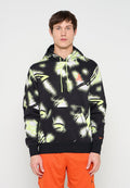 Mann trägt schwarzen Hoodie mit neongelbem und weißem abstraktem Muster sowie neonfarbenen Kordeln, kombiniert mit leuchtend orangen Sportshorts.