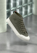 Hohe Sneaker aus olivgrünem Canvas mit braunen Schnürsenkeln, weißer Gummisohle und rotem Akzentdetail an der Rückseite. Glatte Textur und schlichtes Design.