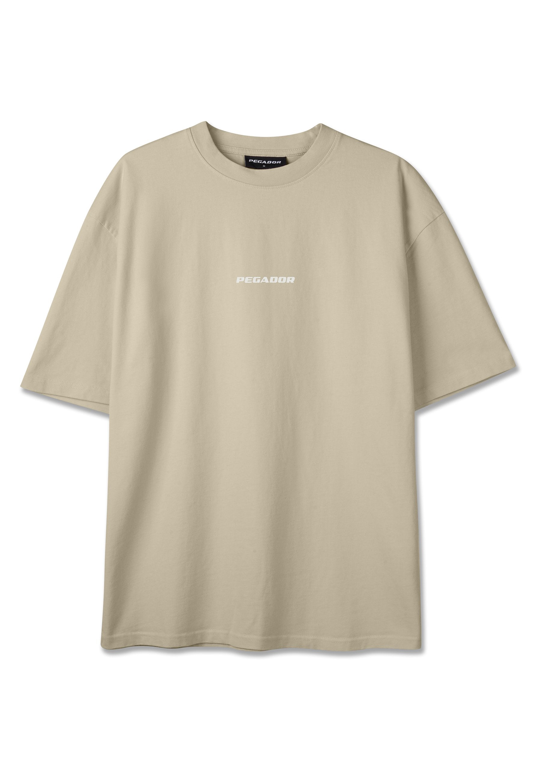 Beiges oversized T-Shirt mit kurzen Ärmeln, rundem Halsausschnitt und kleinem weißem "PEGADOR"-Logo, das mittig auf der Brust platziert ist.