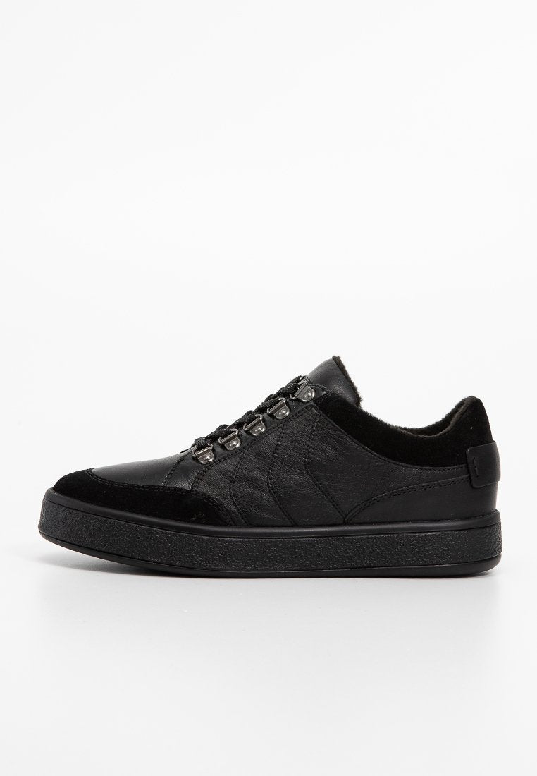 Schwarze Leder-Sneaker mit Wildlederakzenten, Metallösen und einer dicken Gummisohle, von der Seite auf einem weißen Hintergrund gezeigt.