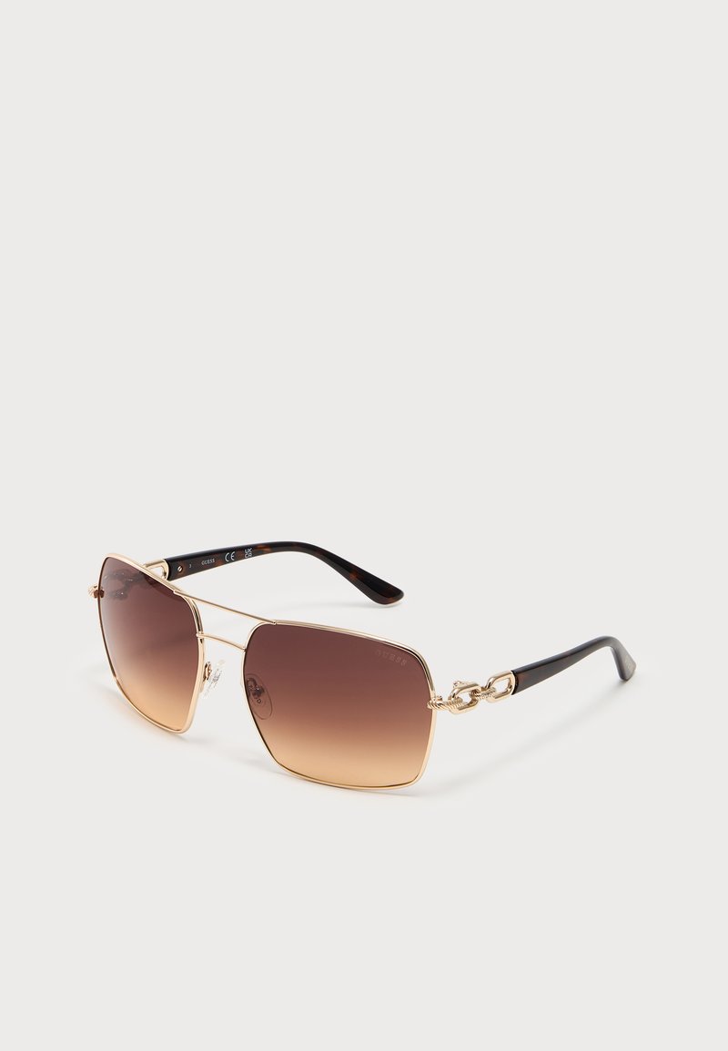 Quadratische braune Sonnenbrille mit Verlaufsgläsern, dünnem goldenem Metallrahmen und schwarzen gebogenen Bügeln auf weißem Hintergrund.
