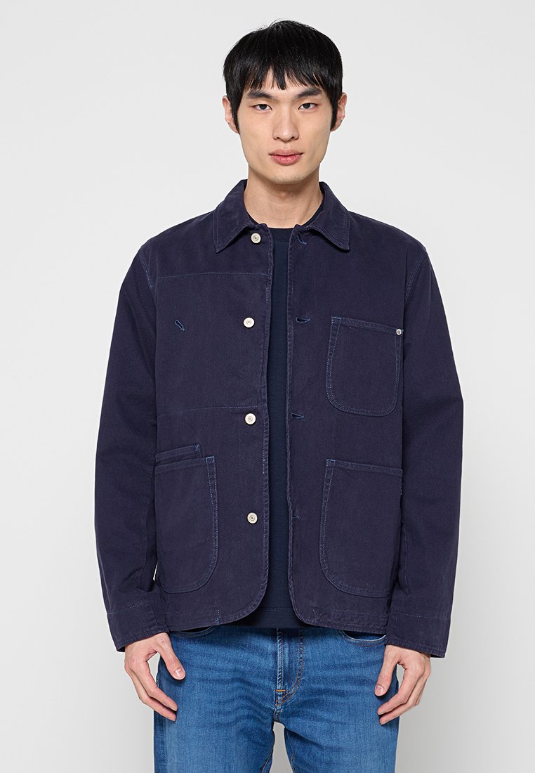 Marineblaue Jacke aus Baumwolle mit durchgehender Knopfleiste, zwei großen Vordertaschen und klassischem Kragen. Glatte Textur und lockere Passform.