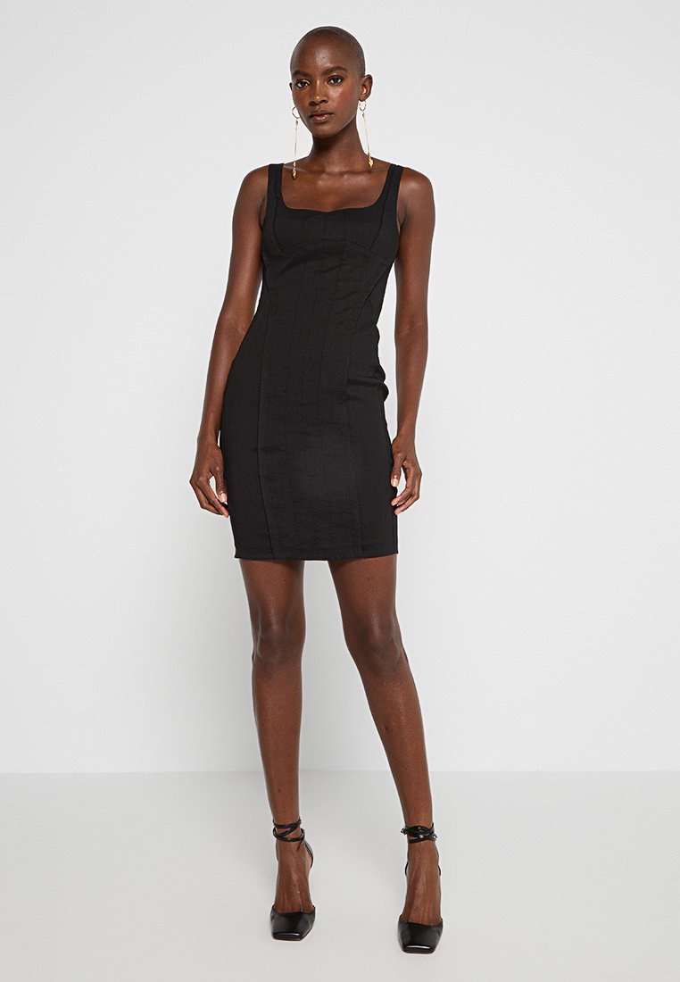 Schwarzes, tailliertes Kleid mit quadratischem Ausschnitt, aus glattem Stoff, mit minimalen Nähdetails und gerader Silhouette.