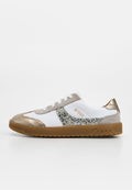 Weißer Sneaker mit goldfarbenem Wildleder an Zehenkappe, Ferse und Verzierungen, glitzerndem silbernem Seitenstreifen, weißen Schnürsenkeln und einer hellbraunen Gummisohle mit der Markierung "1893".