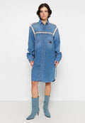 Denim Hemdblusenkleid mit Knopfleiste, langen Ärmeln, zwei Brusttaschen, kontrastierenden Seitenstreifen, knielang, in Hellblau. Begleitet von blauen, knöchelhohen Stiefeln mit Absatz.