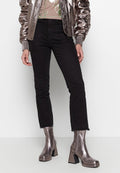 Metallisch glänzende Bomberjacke, beige Oberteil mit grünen Akzenten, schwarze Jeans mit fransigem Saum und glänzende silberne Ankle Boots mit quadratischen Absätzen.