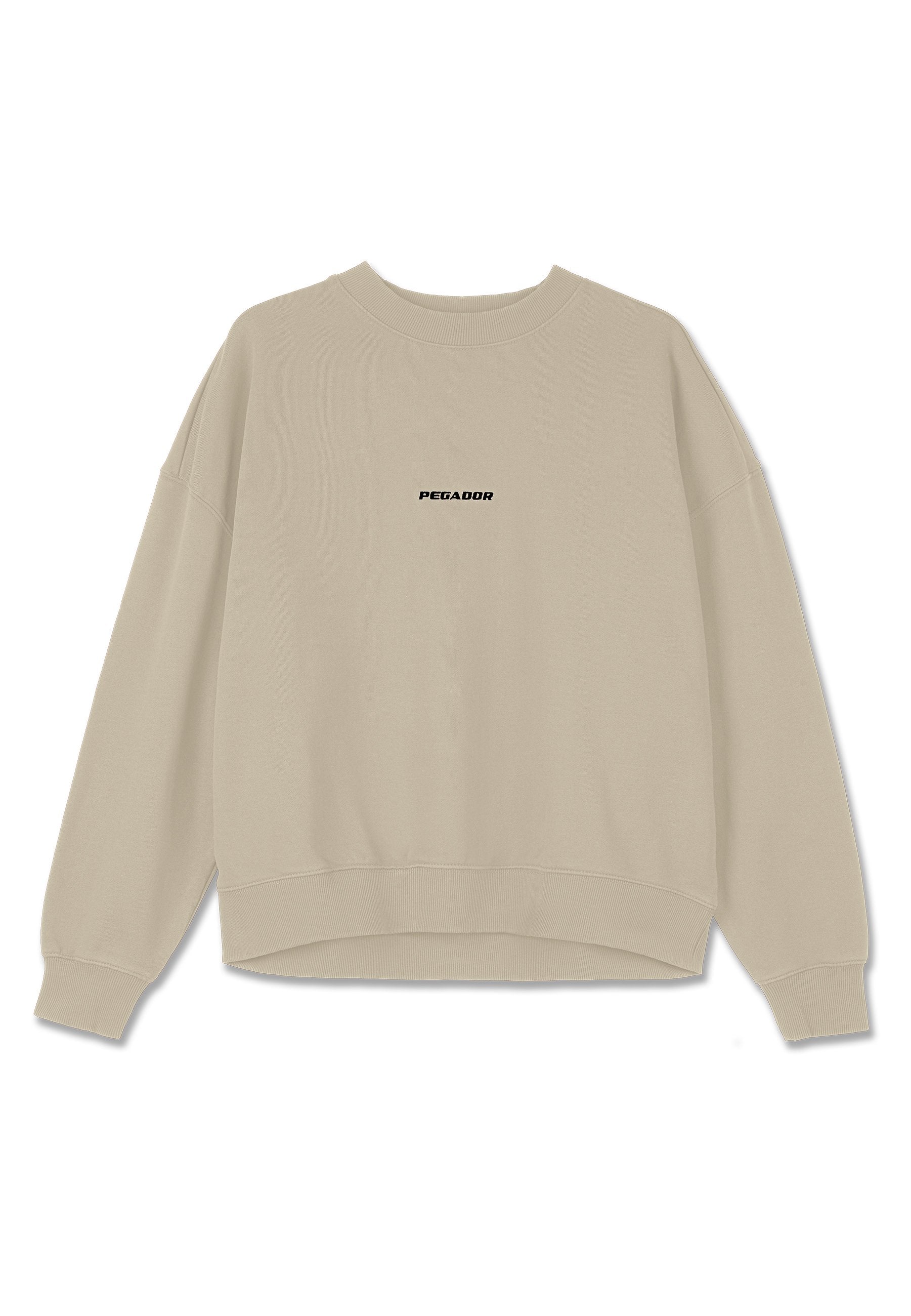 Beige Sweatshirt mit langen Ärmeln, gerippten Bündchen, Saum und Halsausschnitt, mit dem Schriftzug "PEGADOR" in schwarz auf der Brust mittig gedruckt.
