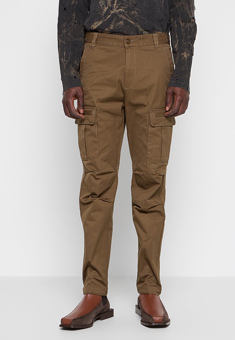Cargo-Hosen aus einem dunkelbraunen Stoff mit leicht strukturierter Oberfläche; verfügen über zwei große Seitentaschen und ein gerades Bein-Design.