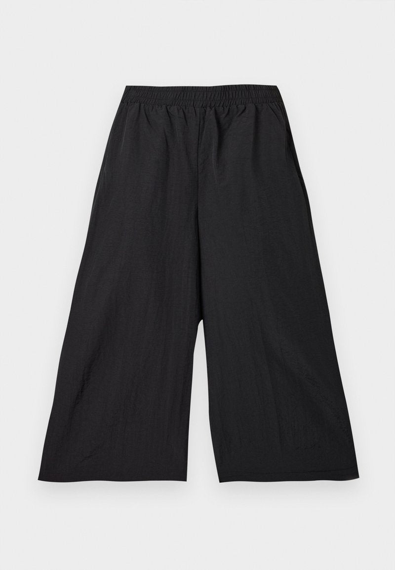 Schwarze, weit geschnittene, verkürzte Hose mit elastischem Bund aus leichtem Stoff, flach auf hellem Hintergrund präsentiert.