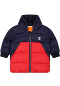 Gefütterte Jacke mit navyblauem oberen Teil und rotem unteren Teil, mit Reißverschluss, gerippten Bündchen und einem Logo auf der Brust.