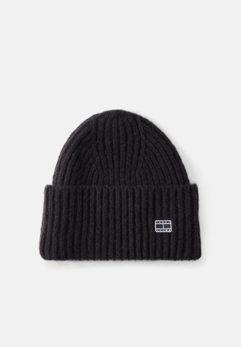 Schwarze gerippte Strickmütze aus weicher Wolle, mit umgeschlagenem Rand und einem kleinen Markenpatch an der Seite. Die Textur ist dick und warm.