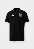 Schwarzes Poloshirt mit kurzen Ärmeln und weißem Adidas-Logo, vier-Sterne-Emblem des Deutschen Fußballverbands und weißen Streifendetails auf den Schultern.