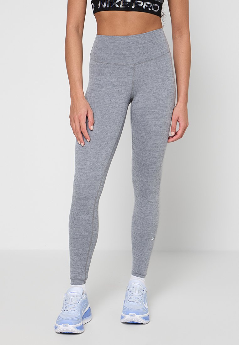 Graue Leggings mit hohem Bund, gefertigt aus einem dehnbaren Material. Getragen mit hellblauen Sportschuhen mit weißen Akzenten.
