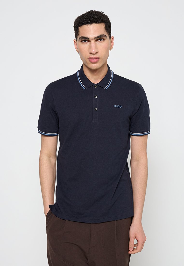 Navy-Poloshirt mit klassischem Design, drei-knopfigem Ausschnitt und kontrastierendem gestreiftem Kragen sowie Ärmelabschlüssen, aus Baumwollstoff gefertigt.