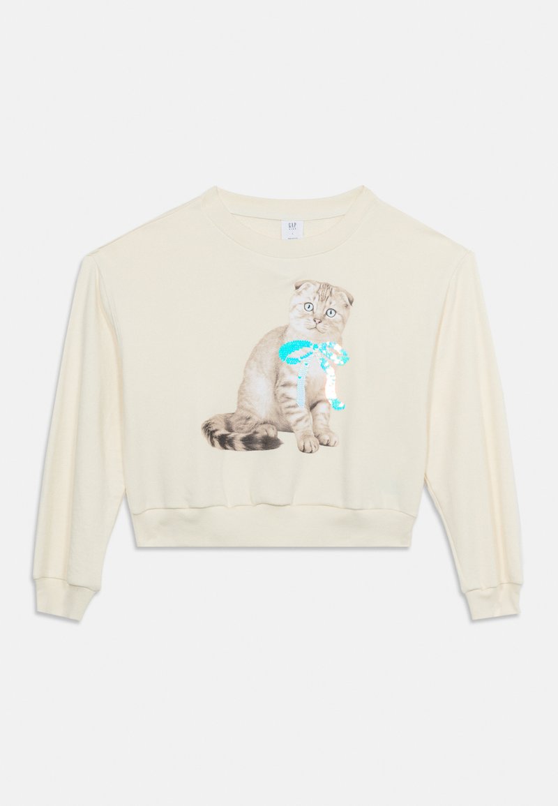 Cremefarbener, langärmeliger, kurz geschnittener Sweatshirt mit einer Grafik einer sitzenden grauen Katze, die eine glänzende türkisfarbene Schleife trägt, auf der Vorderseite.