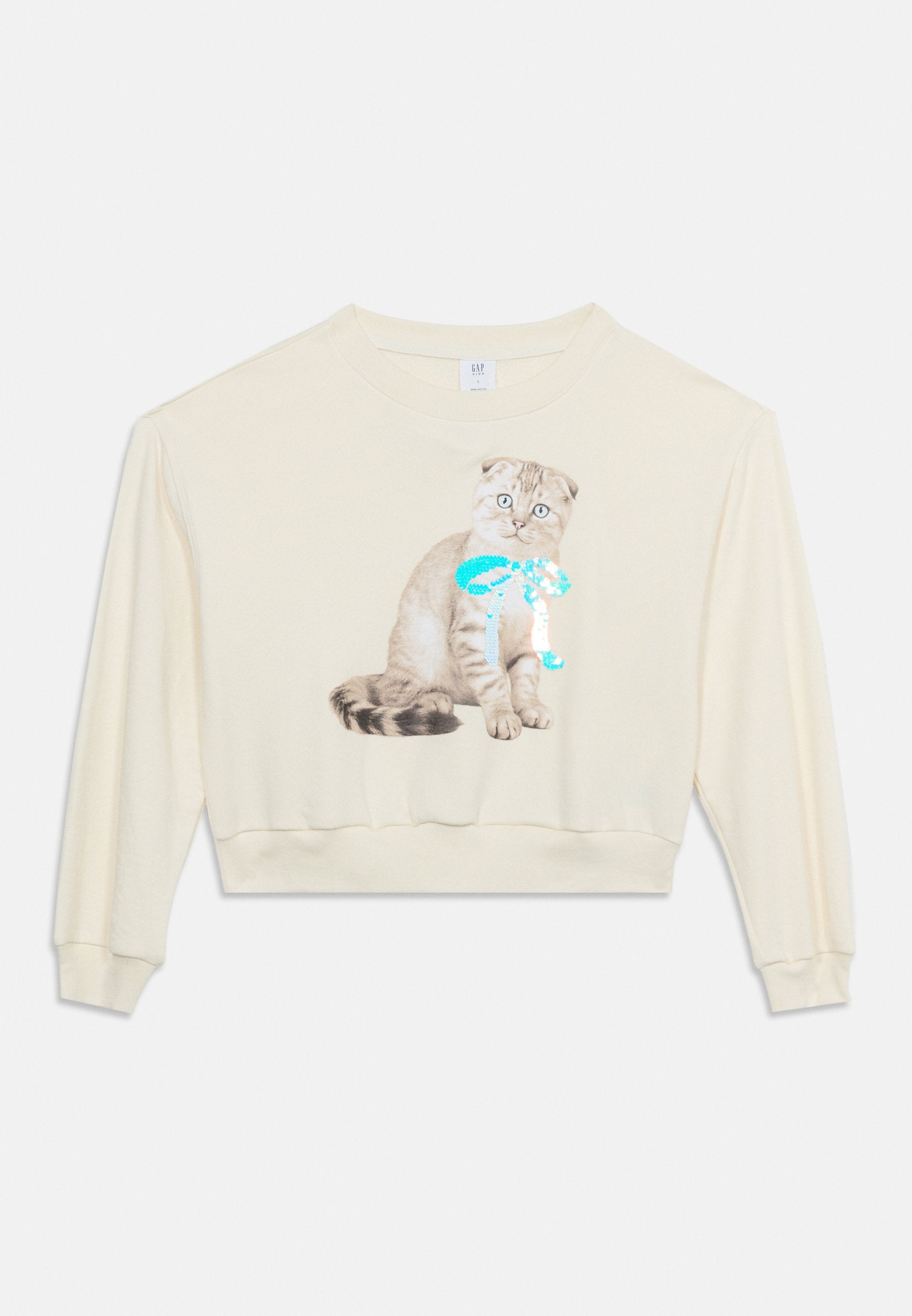 Cremefarbener, langärmeliger, kurz geschnittener Sweatshirt mit einer Grafik einer sitzenden grauen Katze, die eine glänzende türkisfarbene Schleife trägt, auf der Vorderseite.