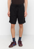 Schwarze Baumwollkurzshorts mit elastischem Bund und Kordelzug. Mit seitlichen Taschen und lockerer Passform, die bis zur Mitte des Oberschenkels reicht.