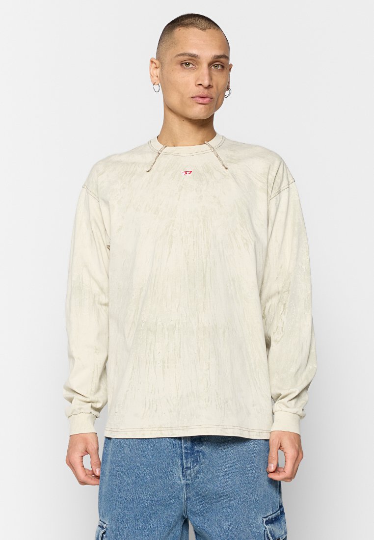 Beige Langarm-T-Shirt mit schwachen vertikalen Mustern, Rundhalsausschnitt und kleinem roten Logo auf der Brust; getragen mit hellblauen Cargo-Hosen.