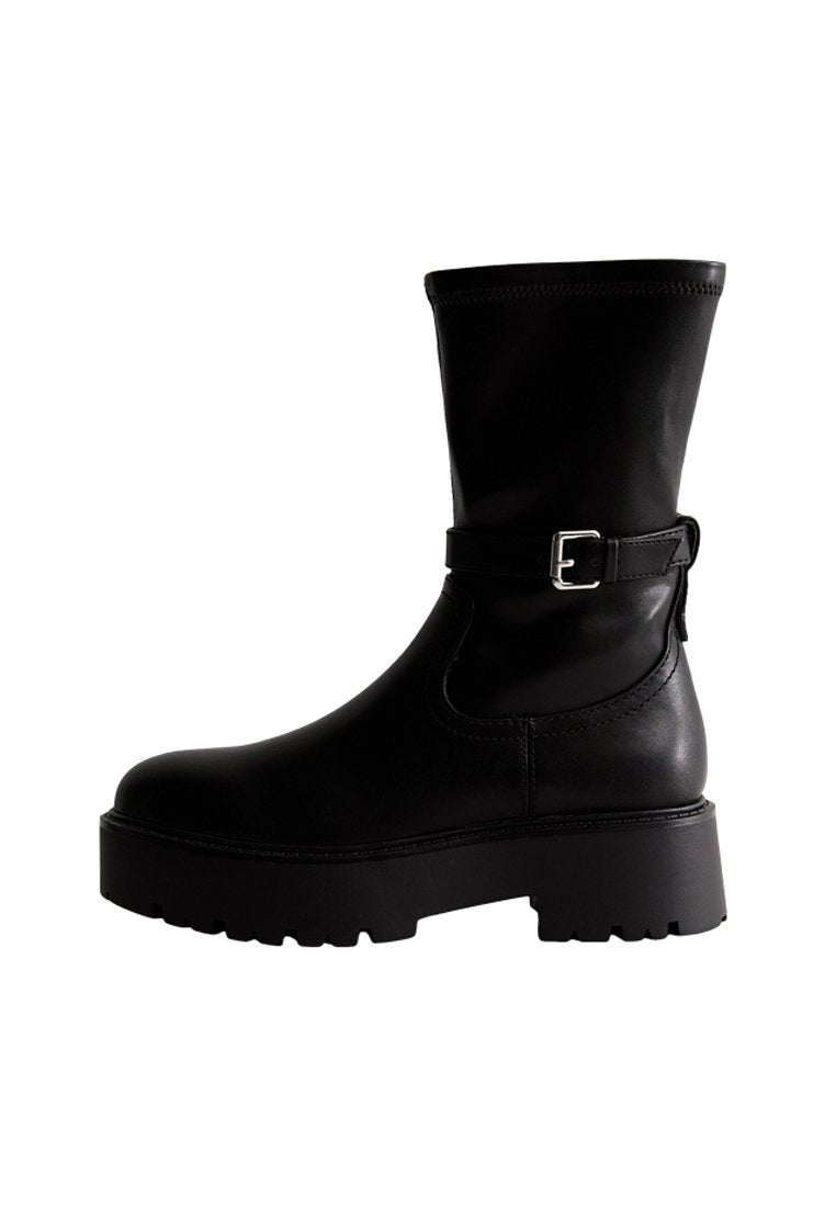 Schwarze Knöchelstiefel mit dicker Sohle, Obermaterial aus glattem Leder und seitlichem Schnallendetail. Mit abgerundetem Zehenbereich und leichtem Absatz.