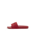 Rote Slide-Sandale mit einem breiten Riemen, auf dem "SAINTS" in erhabenen Buchstaben geprägt ist, flacher Sohle und offener Spitze, im Seitenprofil dargestellt.