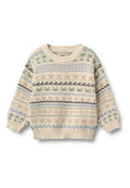 Gestrickter Pullover in Creme mit blauen, grünen und schwarzen Mustern, darunter Wellen, Bäume und Sterne. Rundhalsausschnitt und gerippte Bündchen.