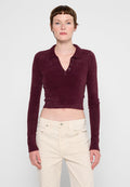 Burgunderfarbiges, cropped Langarm-Polohemd aus weichem, fuzzy Material mit einer Drei-Button-Leiste und einem Kragen. Getragen mit hellen Hosen.