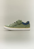 Grüner Sneaker in niedrigem Schnitt mit marineblauer Ferse, gelbem Rand, weißer Sohle, Klettverschluss und Schnürsenkeln, Seitenansicht vor neutralem Hintergrund.