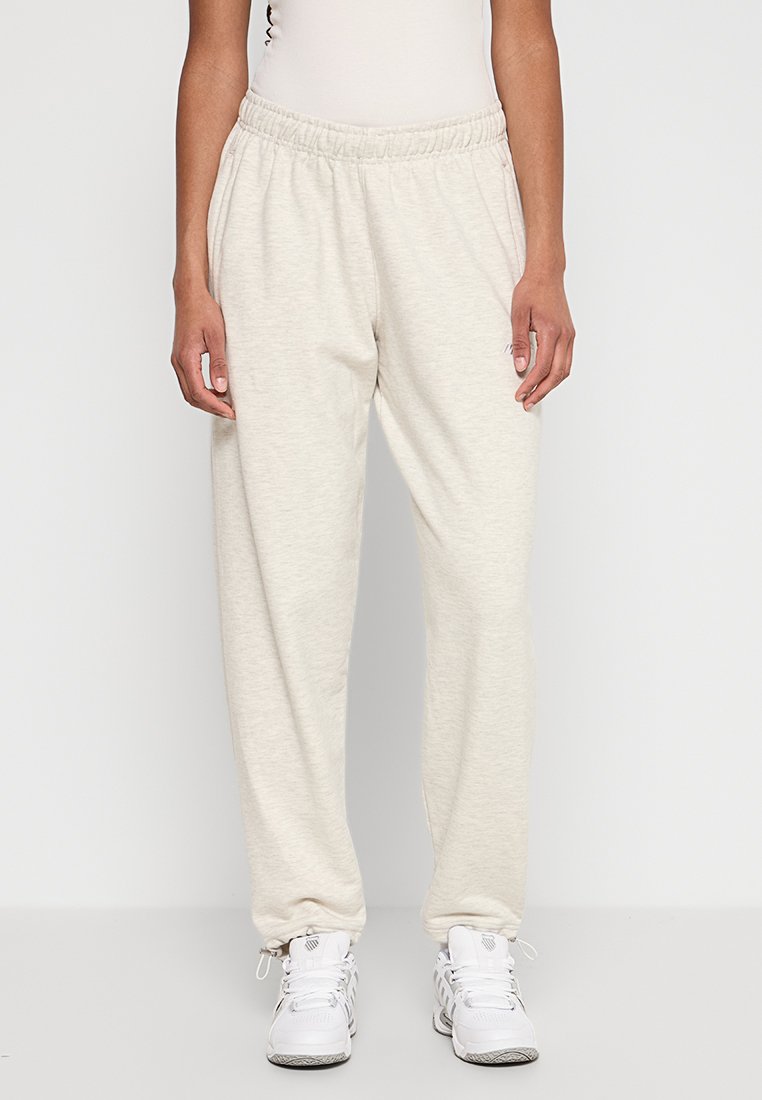 Hellbeige Baumwoll-Sweatpants mit elastischem Bund und schmal zulaufenden Beinabschlüssen, die eine weiche Textur und eine lockere Passform aufweisen.