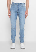 Mann trägt hellblaue Skinny-Jeans und weiße Sneakers, steht vor einem schlichten weißen Hintergrund.