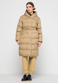 Beige Pufferjacke mit gerafftem Gürtel und silberner Schnalle, ausgestattet mit einem hohen Kragen, langen Ärmeln und steppender Textur. Getragen über hellen Hosen.