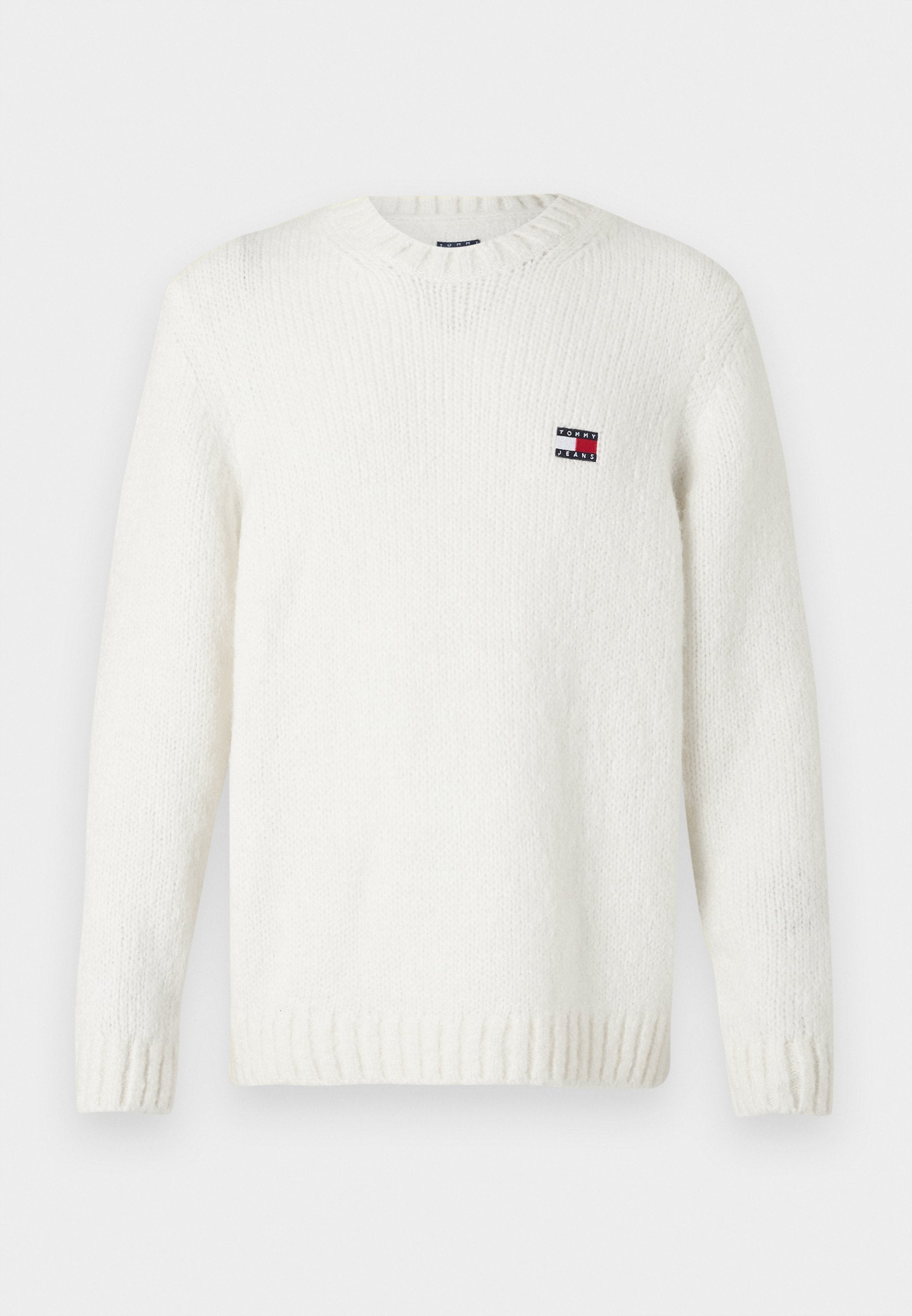 Weißer Strickpullover mit runden Halsausschnitt, gerippten Bündchen und Saum; mit einem kleinen patch in rot, weiß und blau auf der Brust.