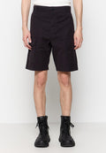 Schwarze Cargo-Shorts aus Baumwolle, mit zwei seitlichen Taschen, einem Knopfverschluss und einem knielangen Schnitt. Getragen mit schwarzen Schnürstiefeln.