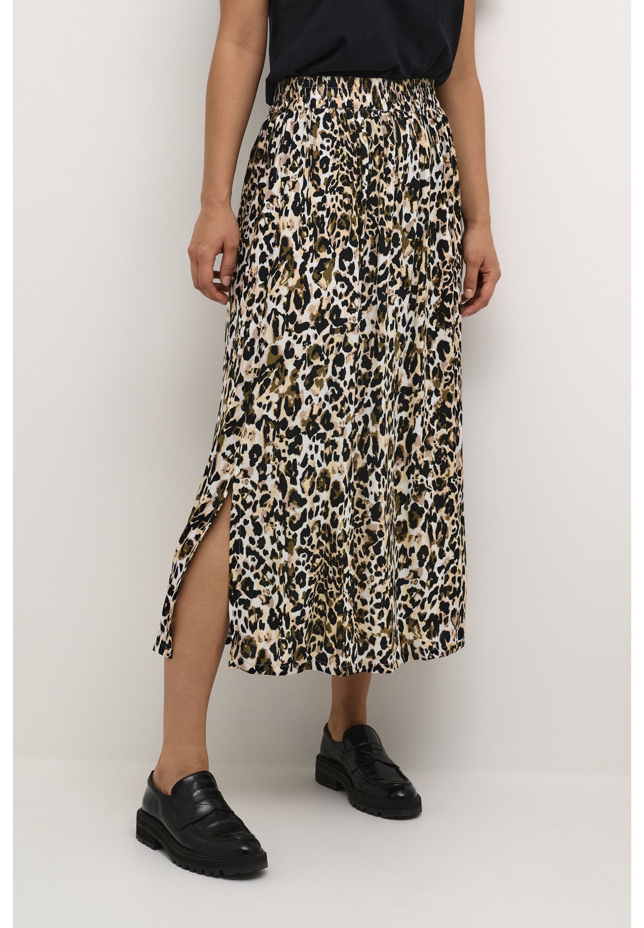 Midikleid aus leichtem Stoff mit Leopardenmuster, elastischem Bund und seitlichen Schlitzen. Kombiniert mit schwarzen Loafers für einen Kontrast.