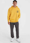 Gelbe Kapuzenjacke mit schwarzem Text, kombiniert mit grauen Jogginghosen und weißen Turnschuhen. Die Kapuzenjacke hat eine Kängurutasche und gerippte Bündchen.